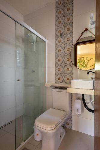 a bathroom with a toilet and a glass shower at Vila Tero 400 metros da praia de Boraceia in São Sebastião