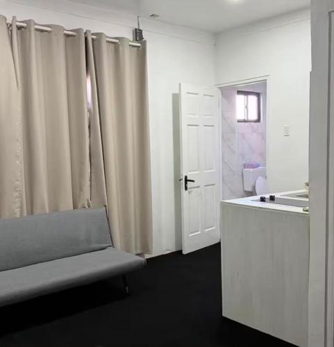 a white room with a door and a chair and a bathroom at Colony Stay in Paramaribo