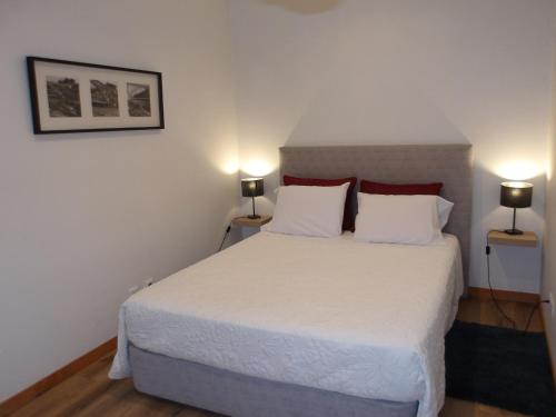 a bedroom with a large white bed with two lamps at Oporto apartment Batalha in Porto