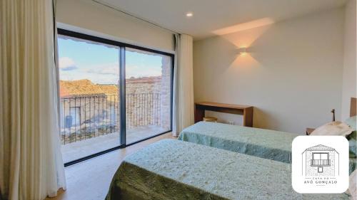 a bedroom with two beds and a large window at Casa do Avô Gonçalo in Mogadouro