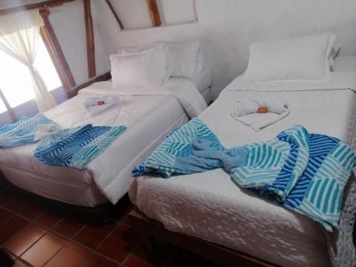 two beds in a room with towels on them at Hostal El Bambú in Inzá