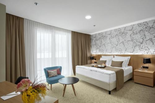 Habitación de hotel con cama y silla azul en Mond, Resort & Entertainment en Šentilj