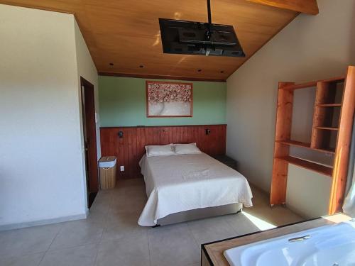 a bedroom with a bed and a tub in it at Sakura da Mantiqueira in Paraisópolis