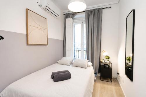 a bedroom with a white bed and a window at Matute Street, Private rooms in Madrid