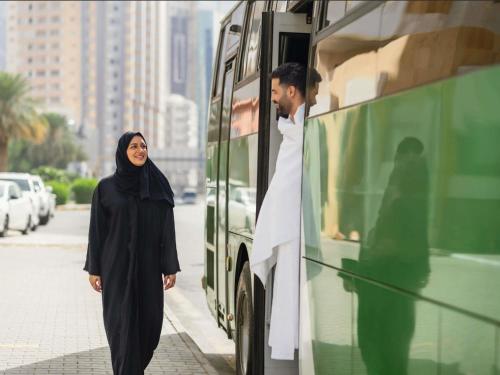 a woman walking next to a green bus at Mercure Makkah Aziziah in Mecca