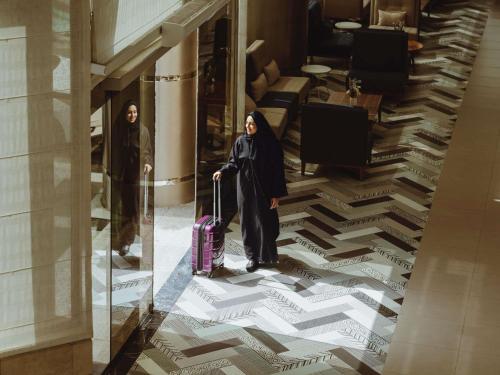 a man and a woman with a suitcase in a building at Mercure Makkah Aziziah in Mecca