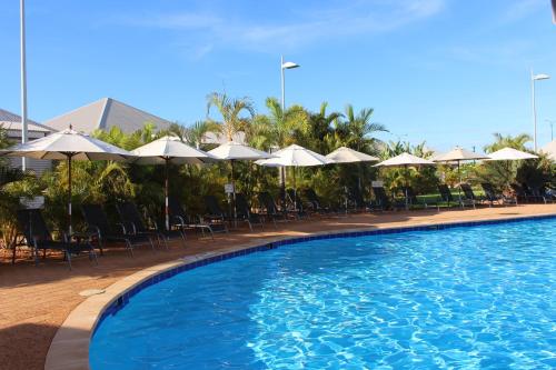 a large swimming pool with chairs and umbrellas at Exmouth Escape Resort in Exmouth