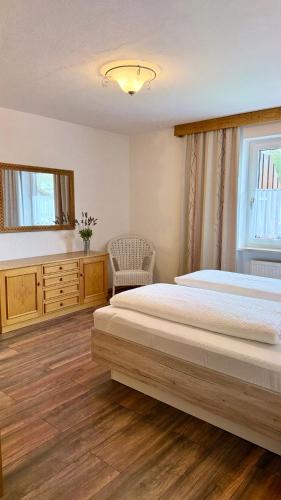a bedroom with a large bed and a chair at Ferienwohnungen Irmengard in Bernau am Chiemsee