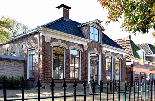 a brick building with a fence in front of it at Gastenverblijf De Oare Keamer Kollum Friesland in Kollum