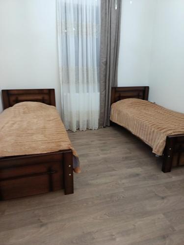 two beds sitting in a room with wooden floors at Sunny Garden House in Ch'aisubani