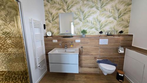 a bathroom with a sink and a toilet and a mirror at Ferienhaus Hafenperle in Dornumersiel
