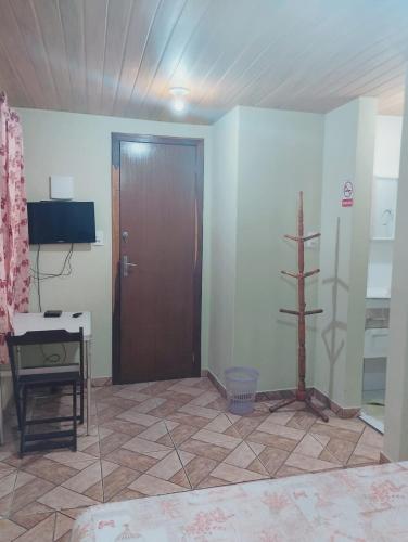 a room with a wooden door and a television at Garcia Suite 2 in Blumenau