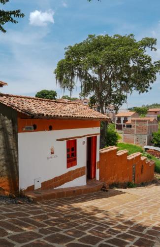 a small white and orange building with a tree in the background at Hotel Tierra Roja in Barichara