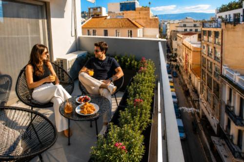 a couple sitting on the balcony of a apartment at Ermou w Jacuzzi Acropolis View Monastiraki in Athens