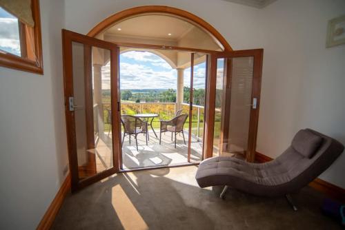 a living room with a couch and a balcony with a table at Thicker Than Water Vineyard - 4 Bedroom Pool in McLaren Vale