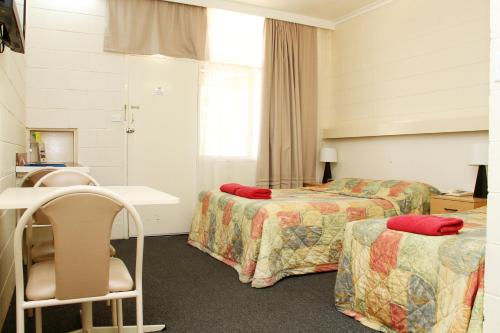 a hotel room with two beds and a chair at Renmark Motor Inn in Renmark