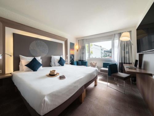 a hotel room with a large bed and a desk at Novotel Chartres in Chartres