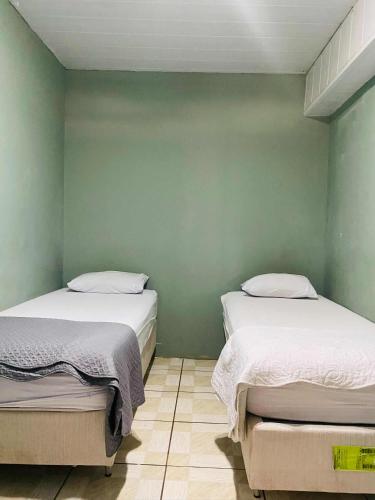 two beds in a room with green walls at quarto aconchegou 1 in Divinópolis