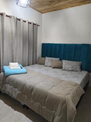 a large bed with a blue headboard in a room at Urku Runa in Humahuaca