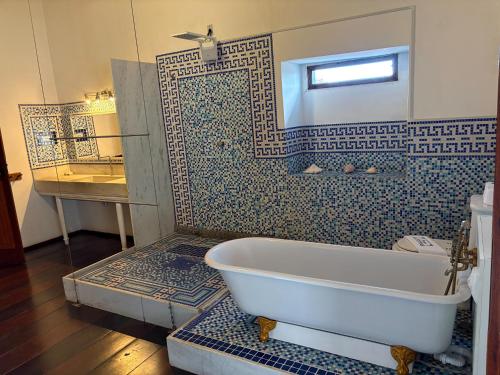 a bathroom with a tub and a blue tiled wall at Casa Lavinia in São Luís