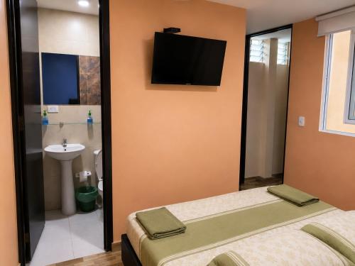 a bathroom with two beds and a tv on the wall at Hostal Avanza in Cali