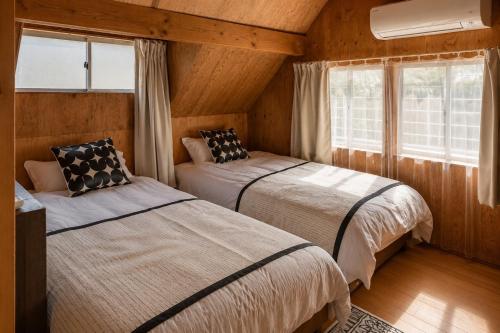 two beds in a room with wooden walls and windows at Alley Oop Hakuba in Hakuba
