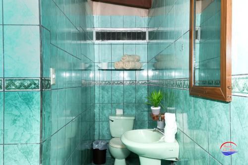 a blue tiled bathroom with a toilet and a sink at Nice Place Hostel in Fortuna