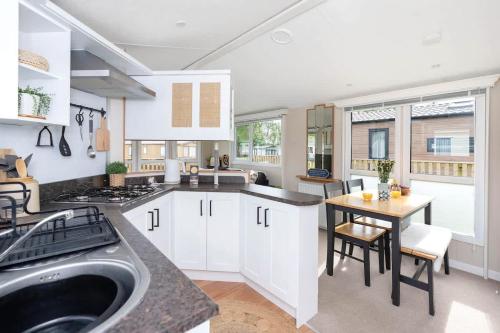 a kitchen with white cabinets and a wooden table at The Chester-2 bed Static Caravan in Oxnam