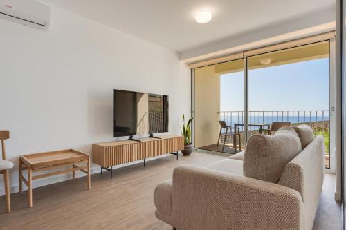 a living room with a couch and a television at Pool Retreat For Families & Romantic Escapes in Câmara de Lobos