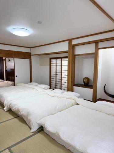 a row of white beds in a room at ASO Uchinomaki Stay in Aso