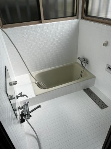 a bathroom with a bath tub and a sink at ASO Uchinomaki Stay in Aso