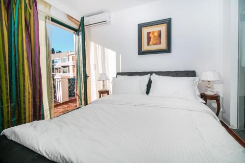 una camera da letto con un grande letto bianco e una finestra di Danezis City Stars Boutique Aparthotel a Città di Rodi