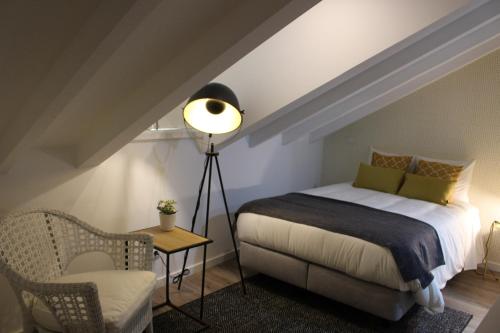 a bedroom with a bed and a lamp and a chair at Jardim da Trindade in Coimbra