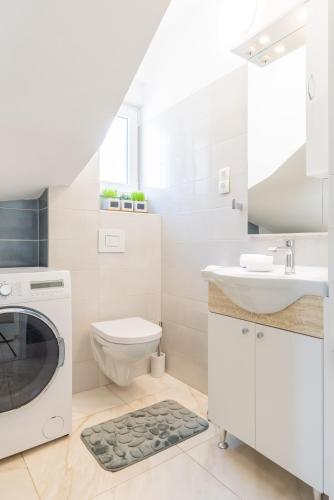 a white bathroom with a sink and a washing machine at Gea Maris Apartment in Kaštela