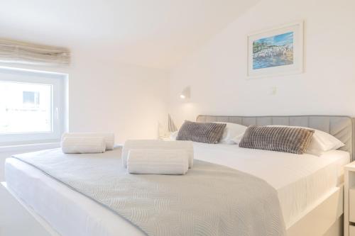 a white bedroom with two beds with white sheets at Gea Maris Apartment in Kaštela