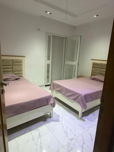 two beds in a room with marble floors at Maison dar allouche in Kelibia