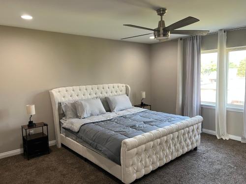 a bedroom with a large white bed with a ceiling fan at Sterling Heights Retreat ! in Sterling Heights