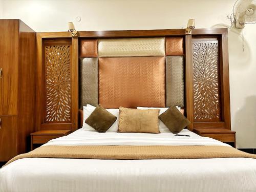 a bedroom with a large bed with a wooden headboard at The Grand Hotel Multan in Multan