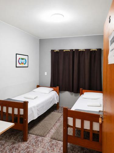 two beds in a room with black curtains at Pouso Tião da Morena in Pirenópolis