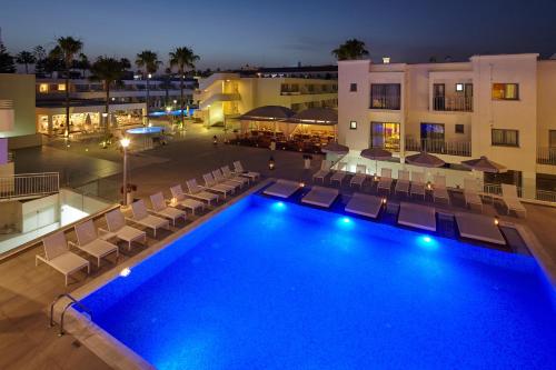 a swimming pool with chairs and a hotel at night at Melpo Antia Hotel & Suites in Ayia Napa