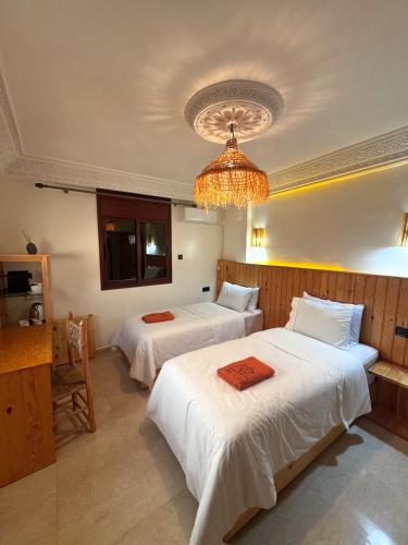 a hotel room with two beds and a chandelier at Taghazout Life in Taghazout