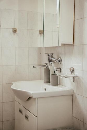 a white bathroom with a sink and a mirror at T&M Apartman in Paraćin