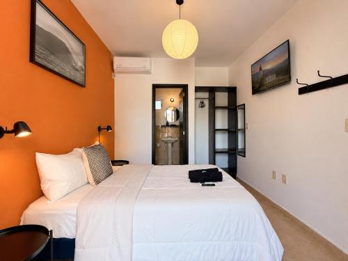 a bedroom with a large white bed with orange walls at La Aurora Puerto Escondido in Puerto Escondido