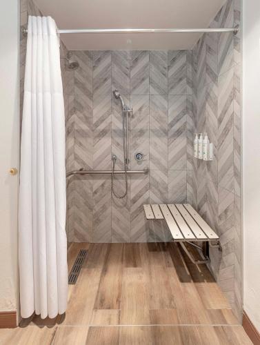 a shower with a bench and a shower curtain at Sandcastle Hotel on the Beach in Pismo Beach
