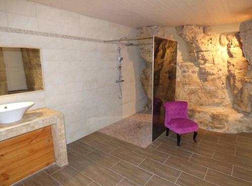 La salle de bains est pourvue d'un fauteuil violet et d'un lavabo. dans l'établissement Hameau de Gratte, à Faugères