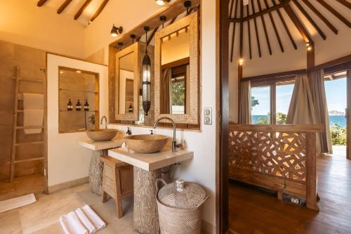 two sinks in a bathroom with two mirrors at Eliana Resort And Spa in Nembrala