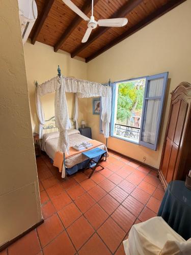 a bedroom with a bed and a large window at Posada del Angel in Colonia del Sacramento