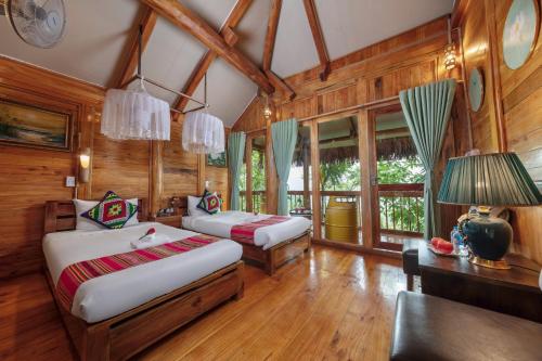 a bedroom with two beds in a room with wooden walls at Gateway Inn PuLuong in Pu Luong