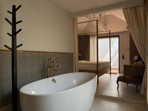 a bathroom with a white bath tub and a bedroom at O - HO Boutique Home in Ban Tai