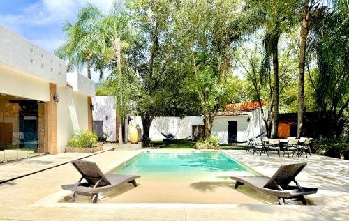 a swimming pool with two chairs and a house at Quinta Encanto in Santiago Nuevo León in Santiago